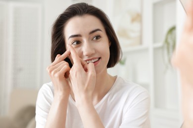 Photo of Beautiful woman putting in contact lens indoors