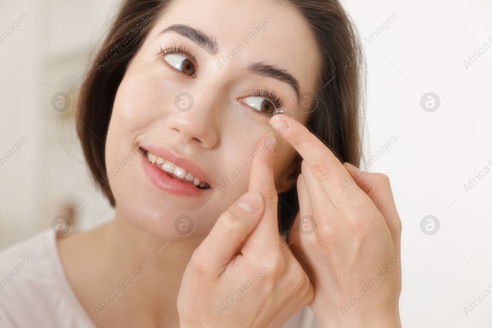 Beautiful woman putting in contact lens indoors, closeup Photo of Beautiful woman putting in contact lens indoors, closeup