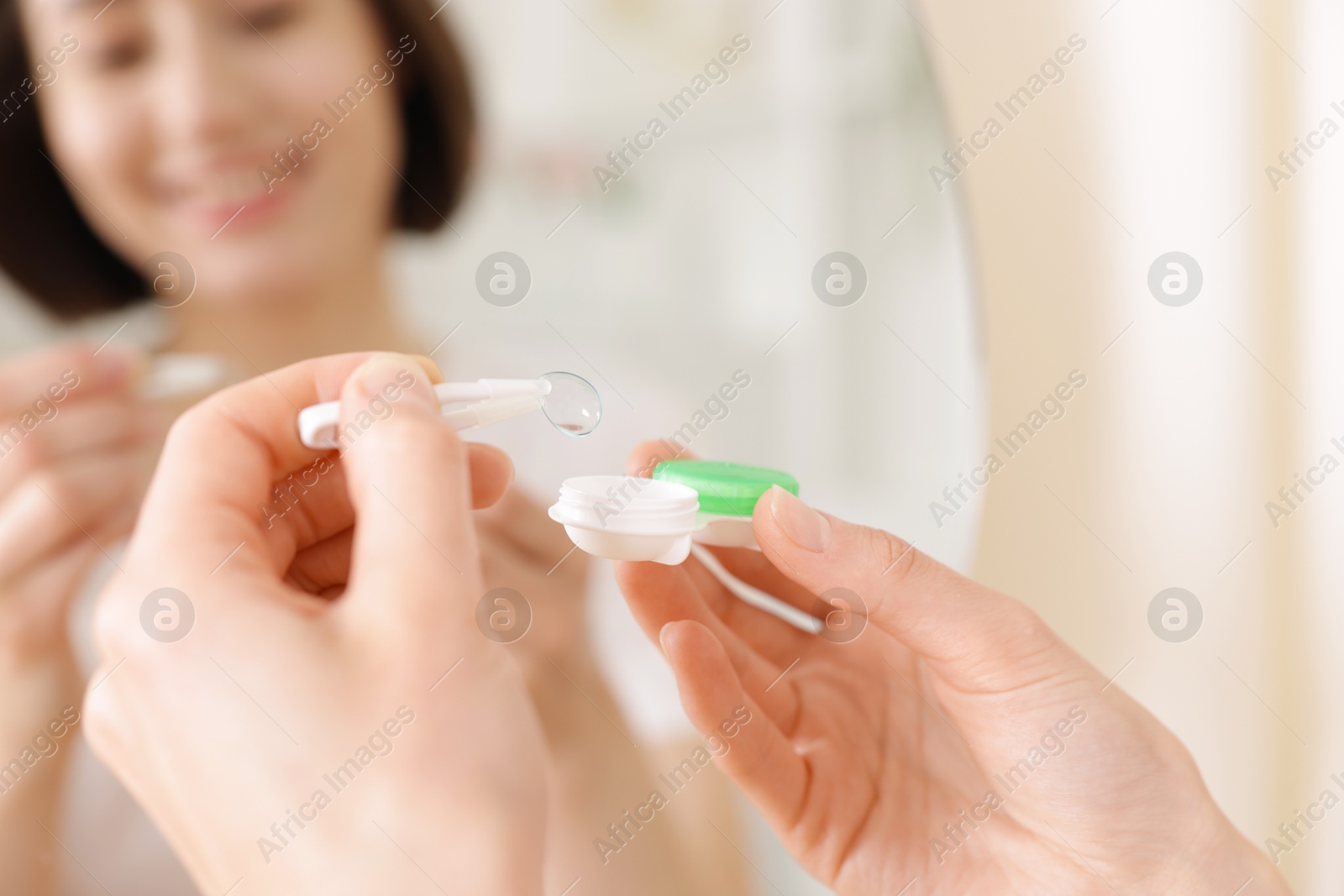Woman taking contact lens out of case indoors, closeup Photo of Woman taking contact lens out of case indoors, closeup