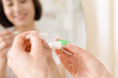 Photo of Woman taking contact lens out of case indoors, closeup