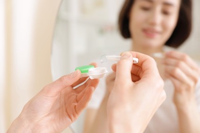 Photo of Woman taking contact lens out of case indoors, closeup
