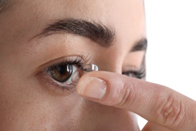 Photo of Woman putting in contact lens on white background, closeup