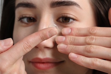 Photo of Beautiful woman putting in contact lens, closeup