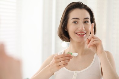 Photo of Woman with contact lens and case indoors. Space for text