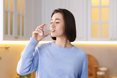 Photo of Young woman drinking water from at home