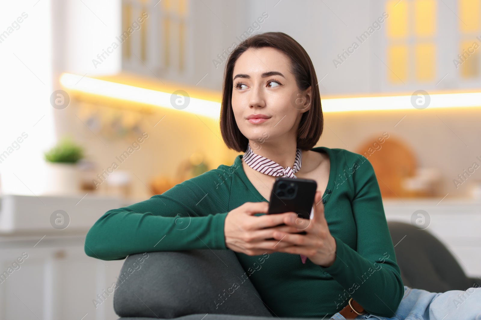 Woman using modern smartphone on sofa at home. Space for text Photo of Woman using modern smartphone on sofa at home. Space for text
