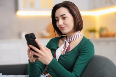 Photo of Woman using modern smartphone on sofa at home