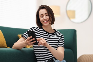 Photo of Beautiful woman using modern smartphone at home