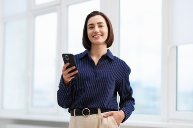 Photo of Beautiful woman using her smartphone in office