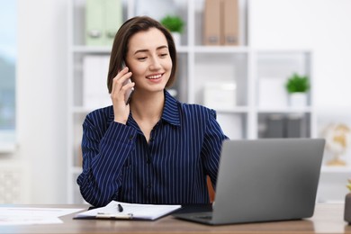 Photo of Beautiful woman talking on phone at desk in office