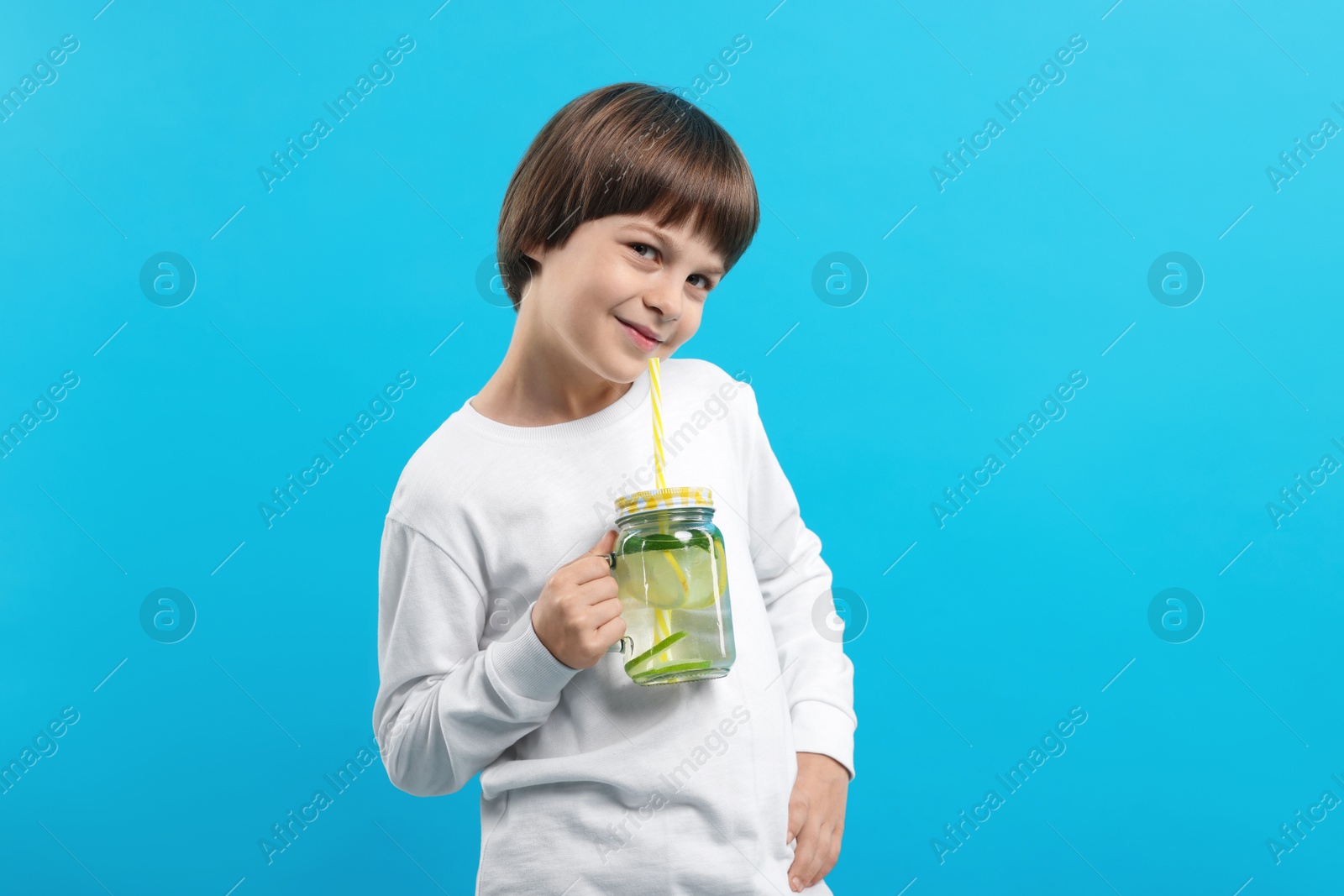 Cute little boy with mason jar of lemonade on light blue background. Refreshing drink Photo of Cute little boy with mason jar of lemonade on light blue background. Refreshing drink