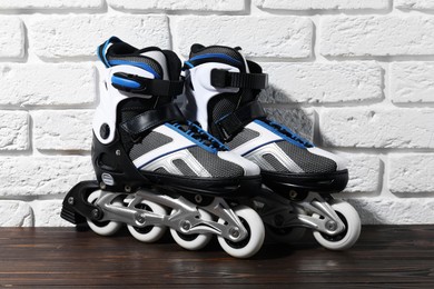 Photo of Pair of roller skates on wooden table near white brick wall