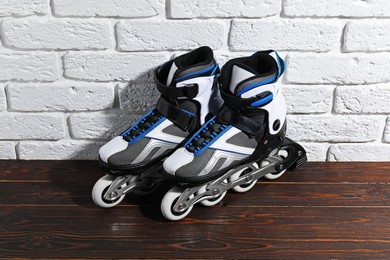 Photo of Pair of roller skates on wooden table near white brick wall, above view