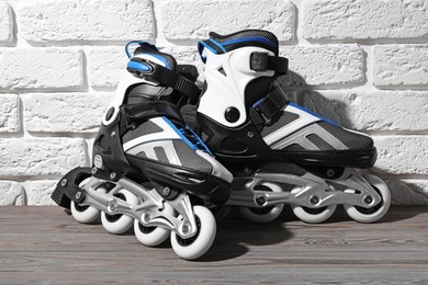 Photo of Pair of roller skates on wooden table near white brick wall