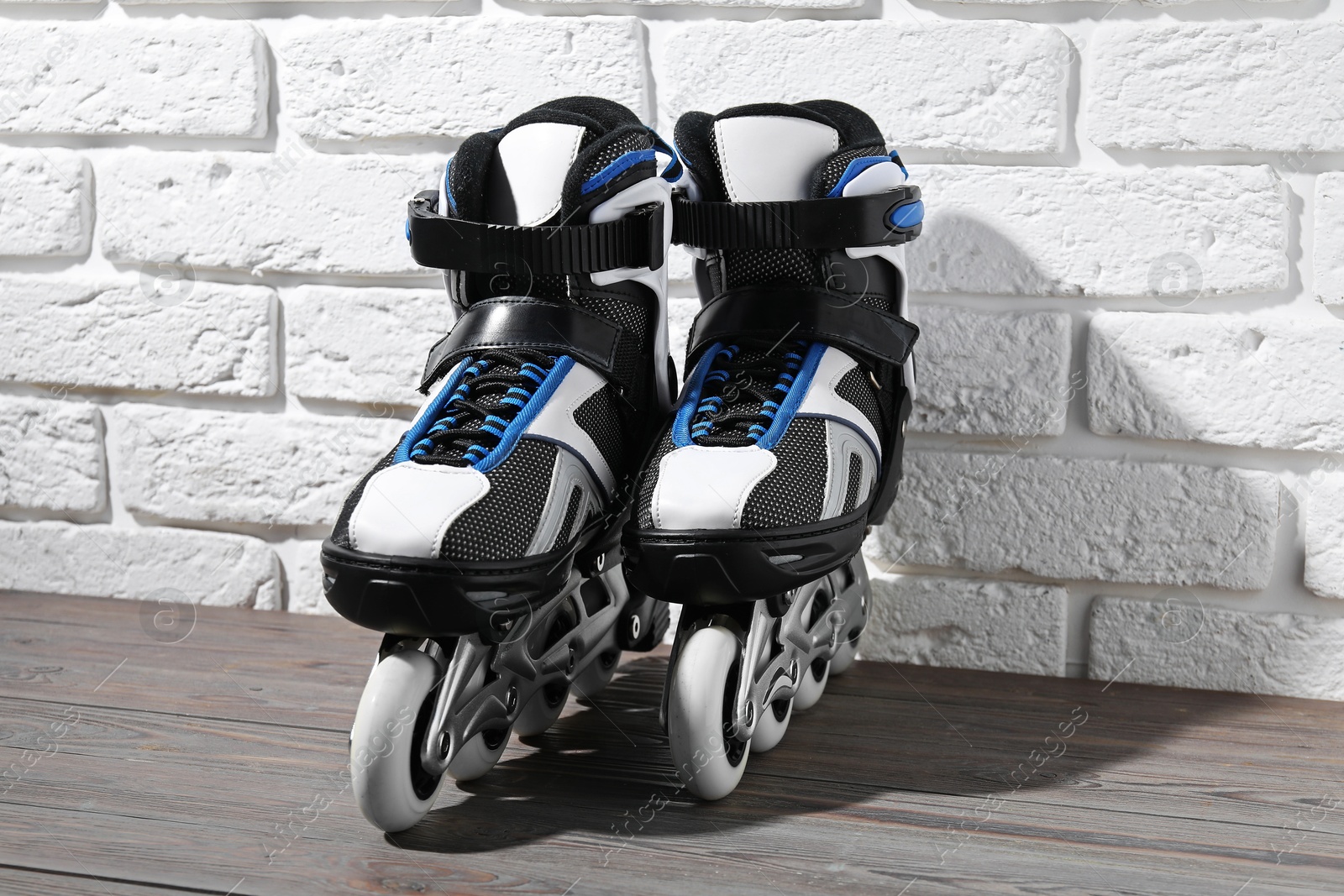 Pair of roller skates on wooden table near white brick wall Photo of Pair of roller skates on wooden table near white brick wall