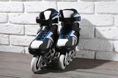 Photo of Pair of roller skates on wooden table near white brick wall