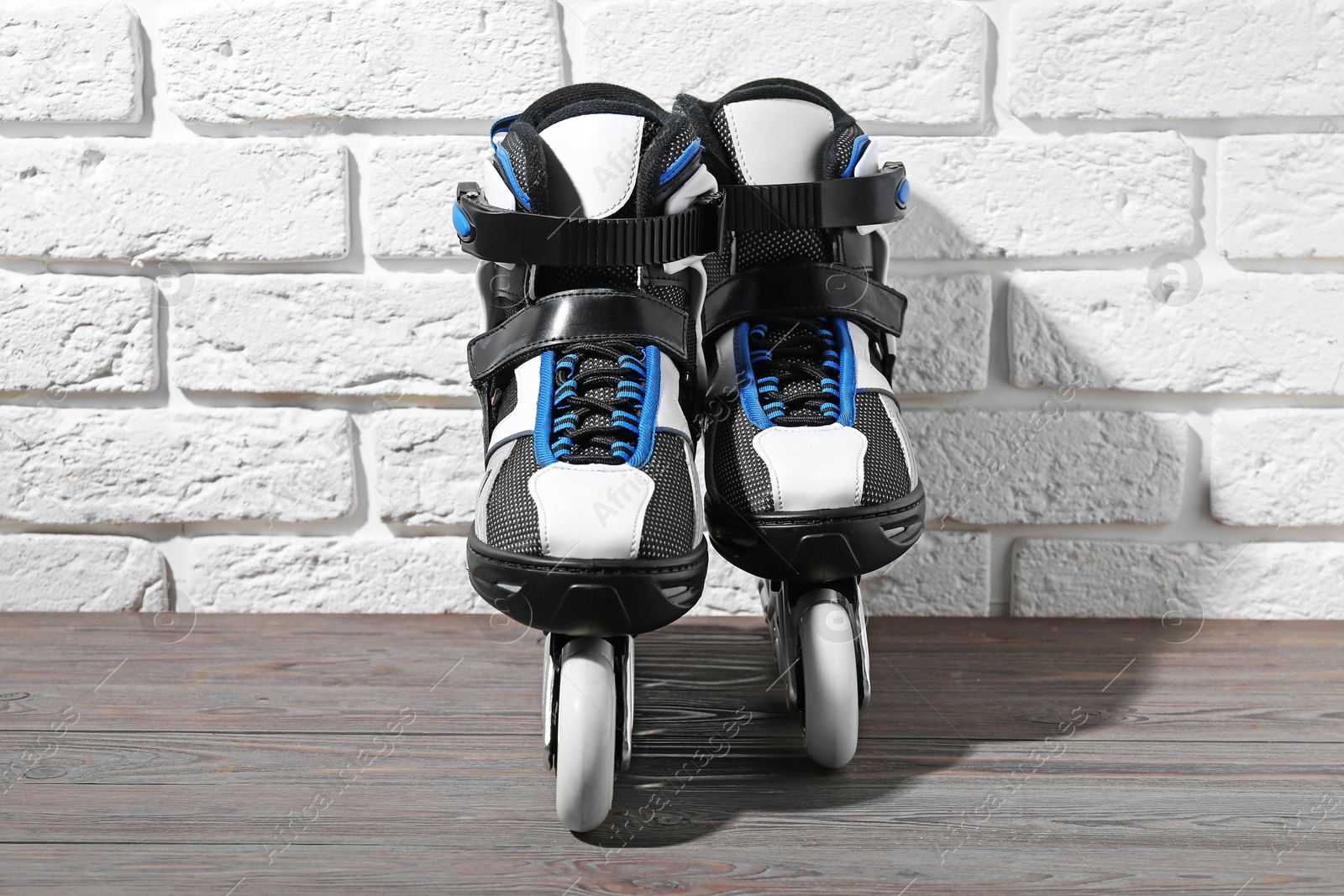 Pair of roller skates on wooden table near white brick wall Photo of Pair of roller skates on wooden table near white brick wall