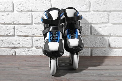 Photo of Pair of roller skates on wooden table near white brick wall