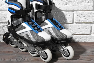 Photo of Pair of roller skates on wooden table near white brick wall, closeup