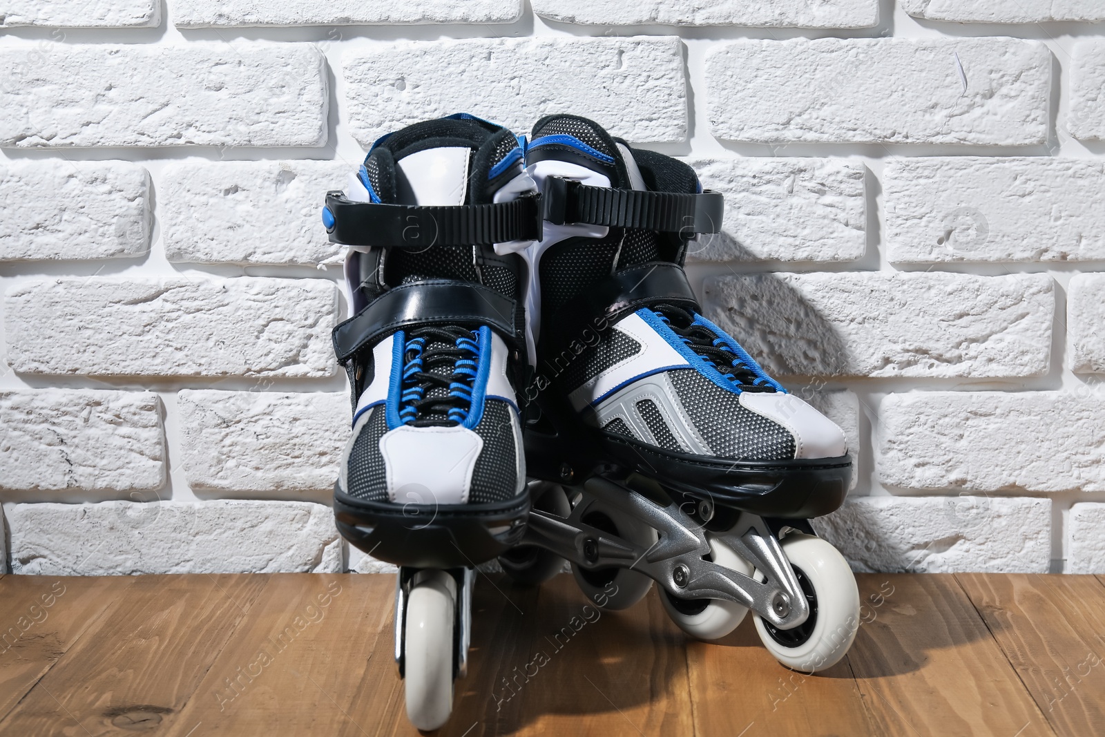 Pair of roller skates on wooden table near white brick wall Photo of Pair of roller skates on wooden table near white brick wall