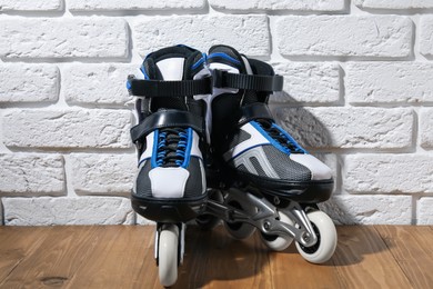 Photo of Pair of roller skates on wooden table near white brick wall