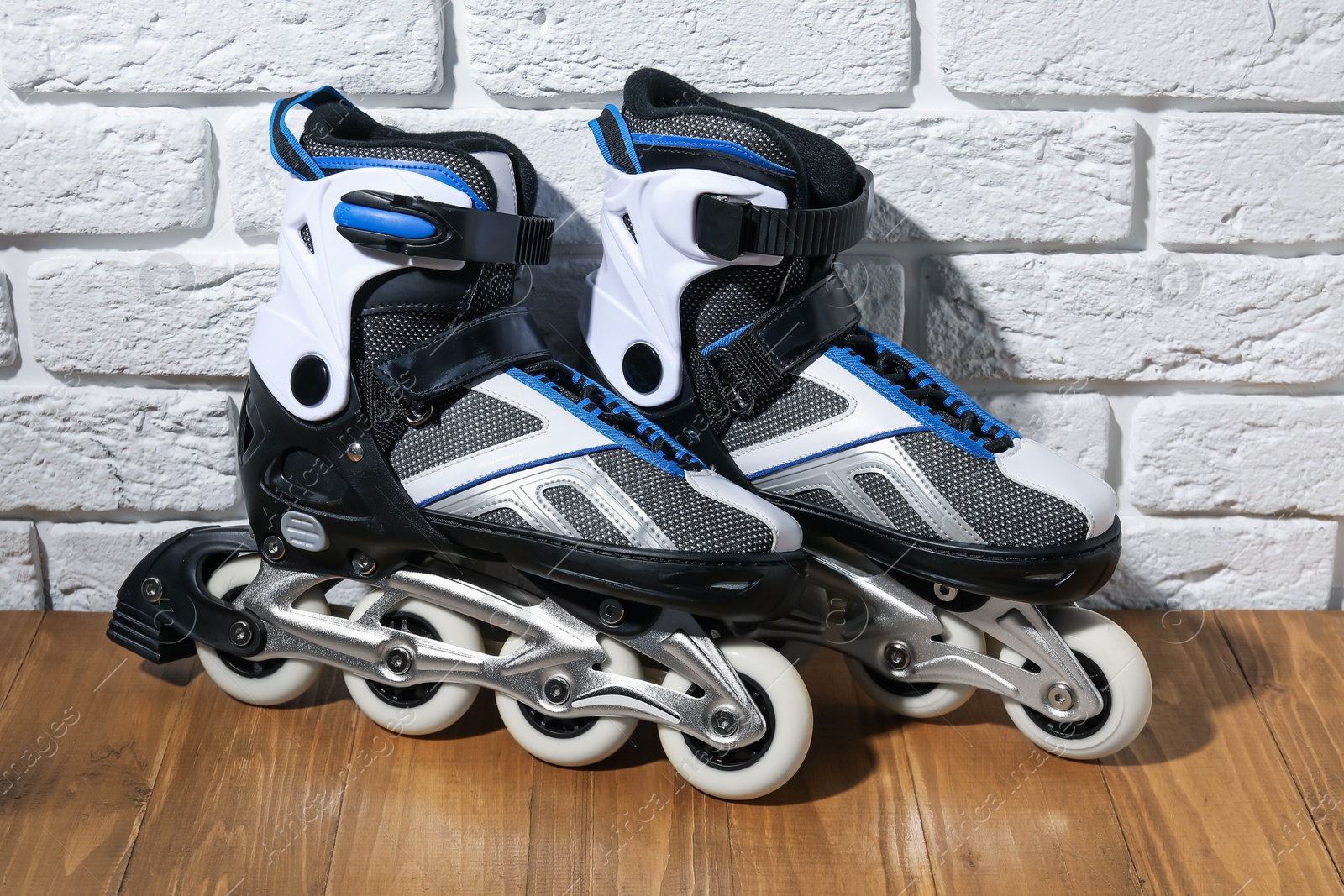 Pair of roller skates on wooden table near white brick wall Photo of Pair of roller skates on wooden table near white brick wall