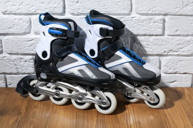 Photo of Pair of roller skates on wooden table near white brick wall