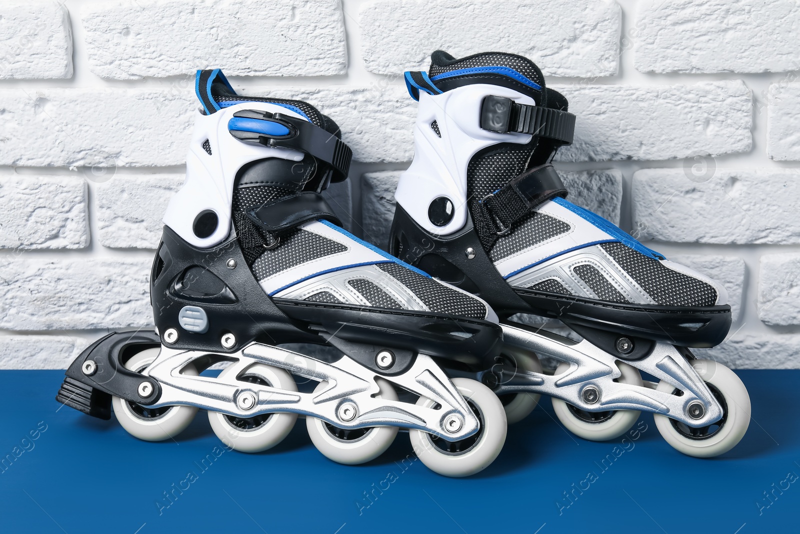 Pair of roller skates on blue table near white brick wall Photo of Pair of roller skates on blue table near white brick wall