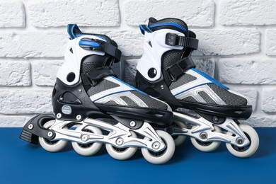 Photo of Pair of roller skates on blue table near white brick wall