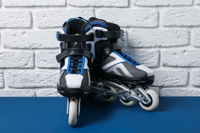 Photo of Pair of roller skates on blue table near white brick wall