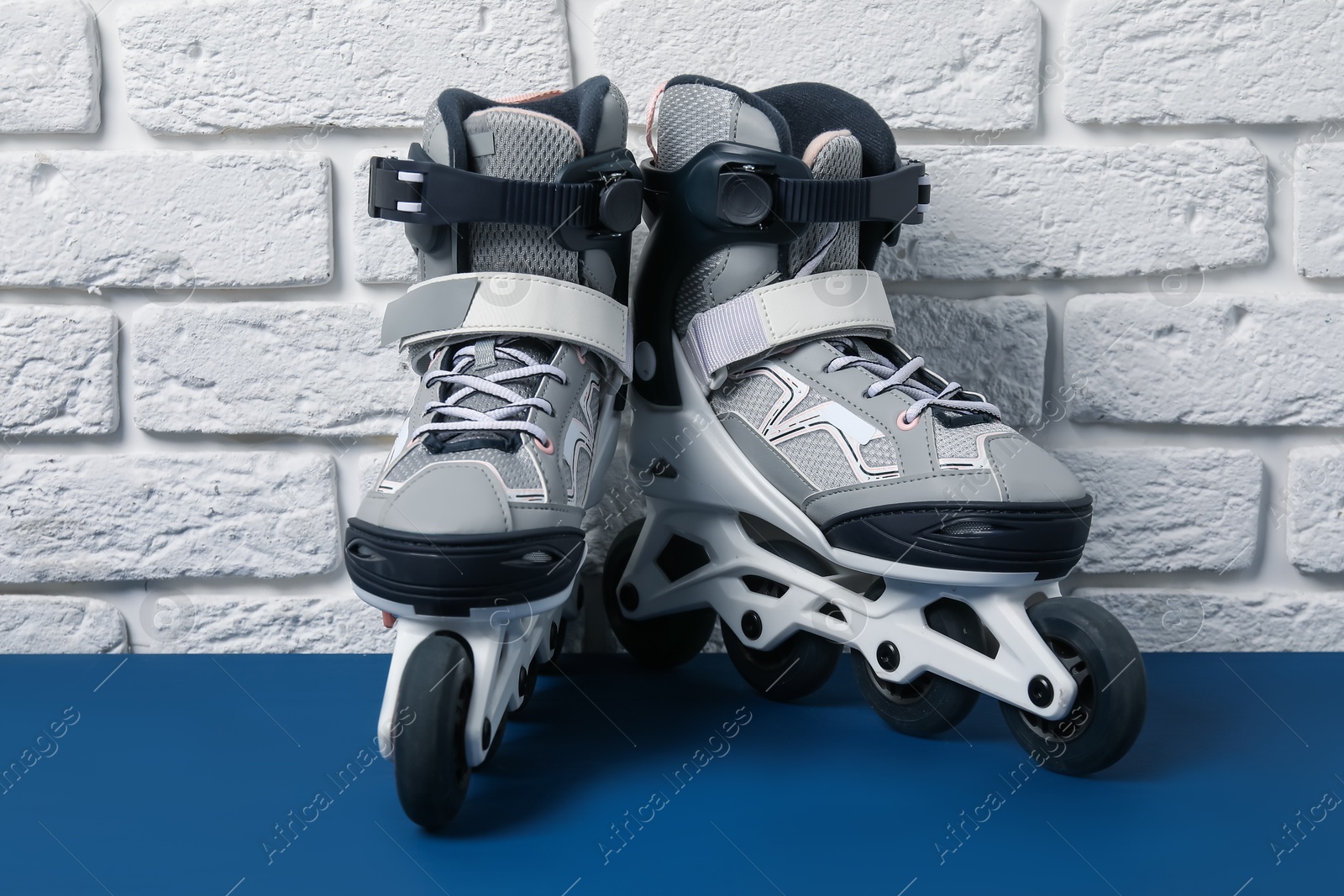 Pair of roller skates on blue table near white brick wall Photo of Pair of roller skates on blue table near white brick wall