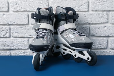 Photo of Pair of roller skates on blue table near white brick wall