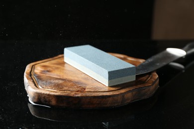 Photo of Sharpener and knife on black mirror surface, closeup