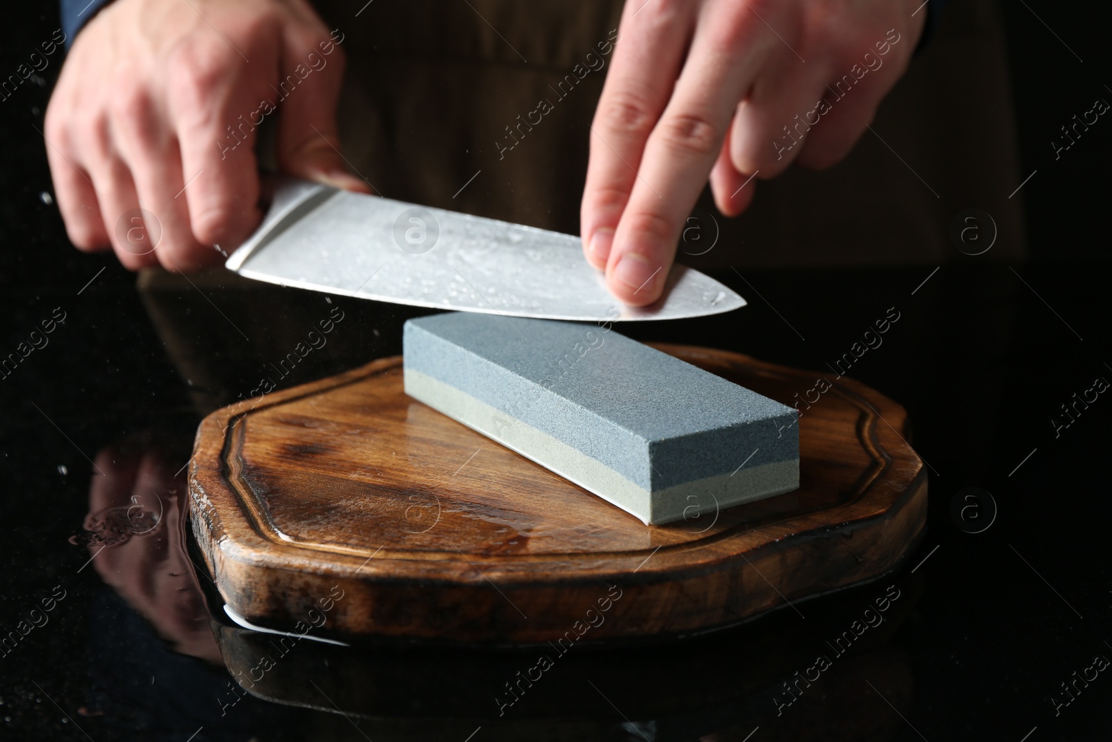Man sharpening knife with sharpener at mirror table, closeup Photo of Man sharpening knife with sharpener at mirror table, closeup