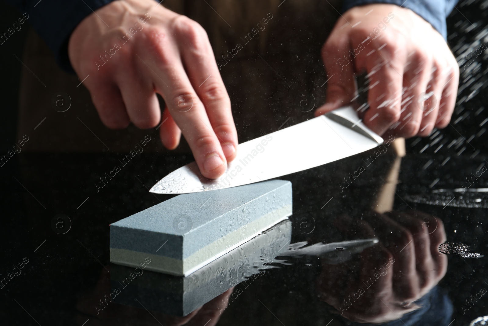 Man sharpening knife with sharpener at mirror table, closeup Photo of Man sharpening knife with sharpener at mirror table, closeup