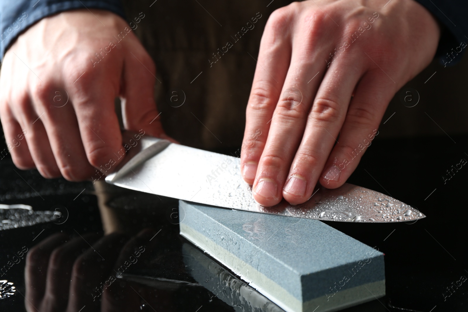 Man sharpening knife with sharpener at mirror table, closeup Photo of Man sharpening knife with sharpener at mirror table, closeup