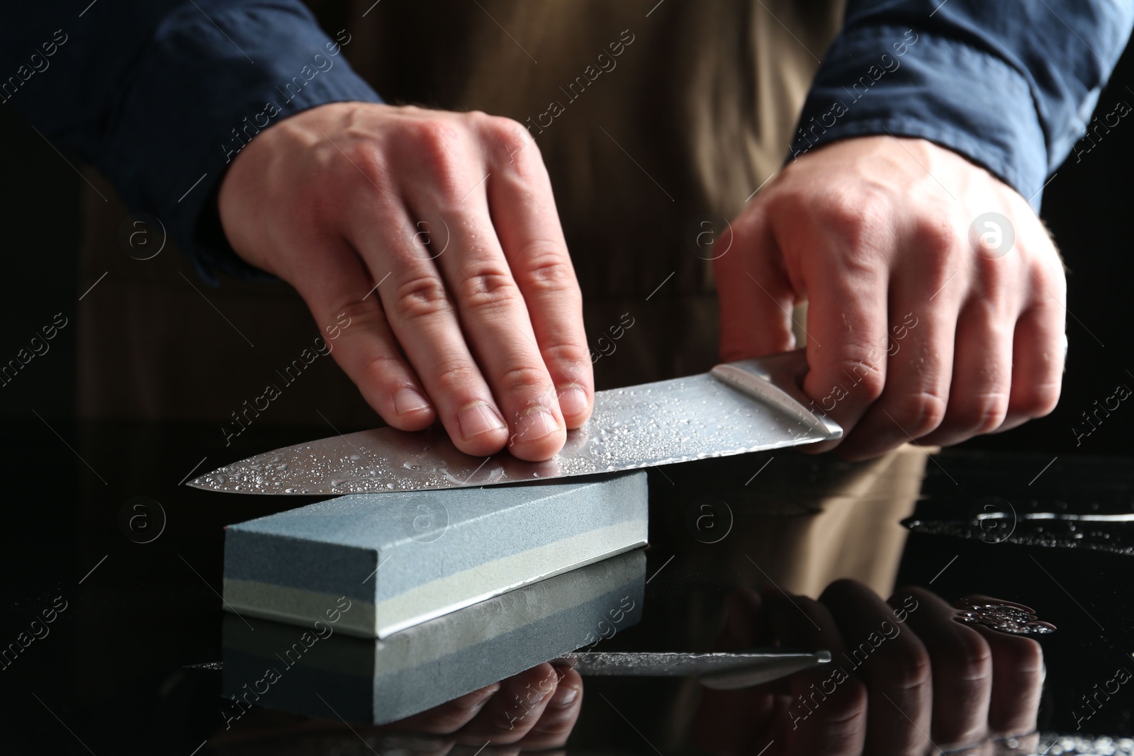 Man sharpening knife with sharpener at mirror table, closeup Photo of Man sharpening knife with sharpener at mirror table, closeup