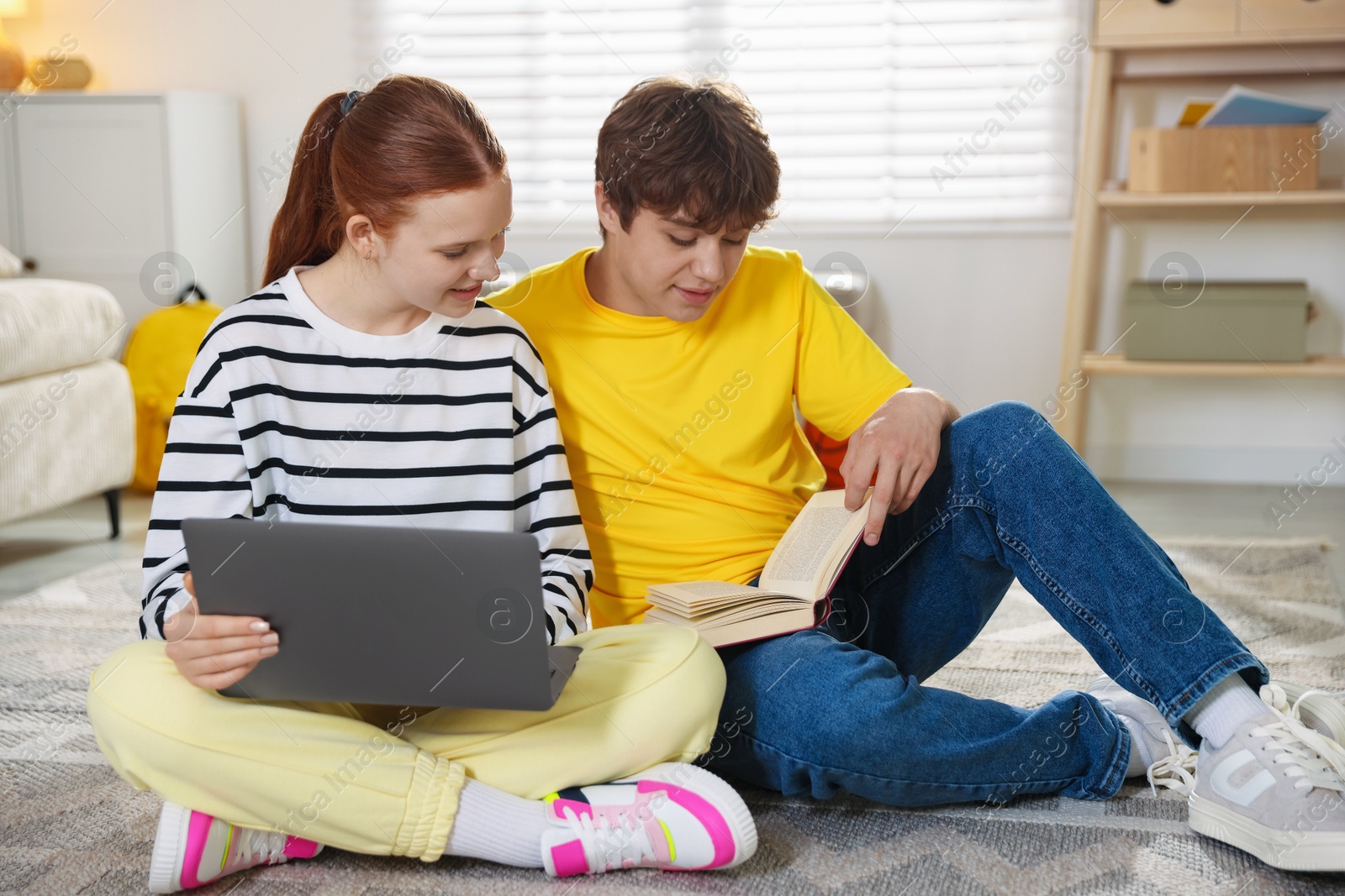 Teenage students with laptop studying on floor at home Photo of Teenage students with laptop studying on floor at home