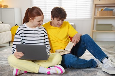 Photo of Teenage students with laptop studying on floor at home
