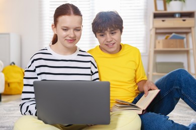 Photo of Teenage students with laptop studying on floor at home