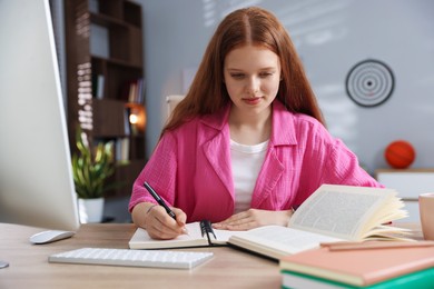 Photo of Teenage student taking notes while studying at table indoors