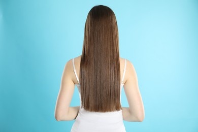 Photo of Woman with perfect long hair on light blue background, back view