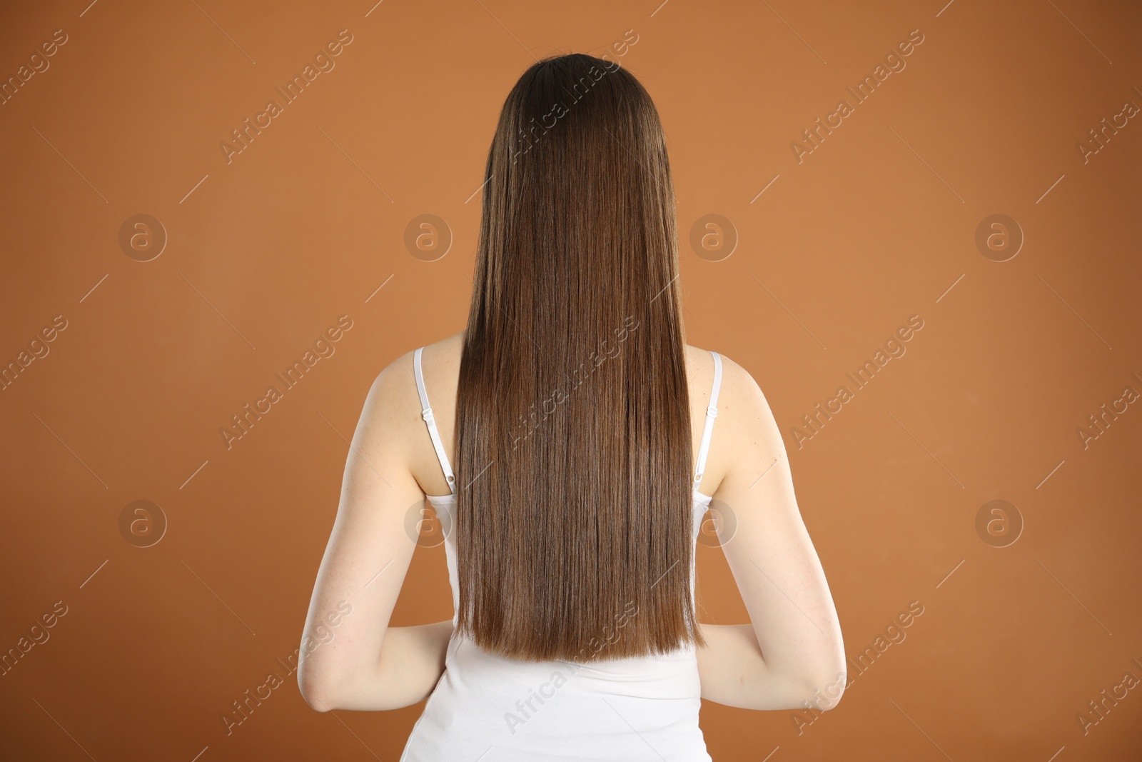 Photo of Woman with perfect long hair on brown background, back view