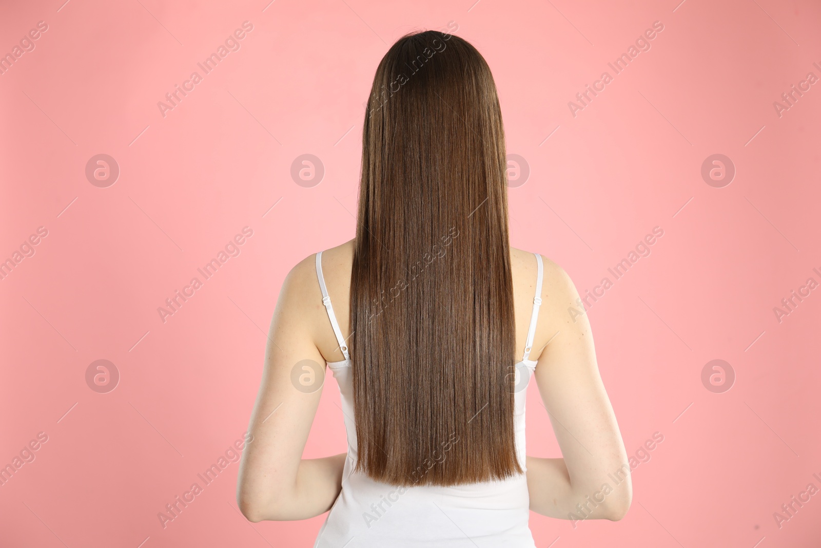 Photo of Woman with perfect long hair on light pink background, back view
