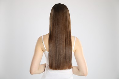 Photo of Woman with perfect long hair on light background, back view