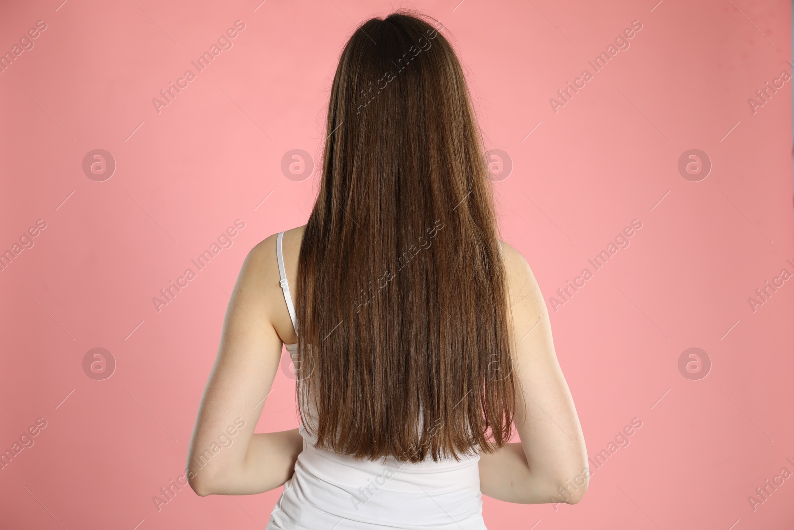 Photo of Woman with long hair on light pink background, back view