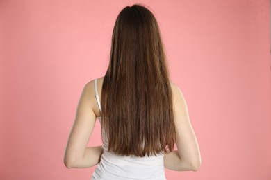 Photo of Woman with long hair on light pink background, back view