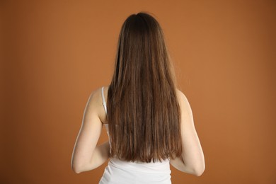 Photo of Woman with long hair on brown background, back view