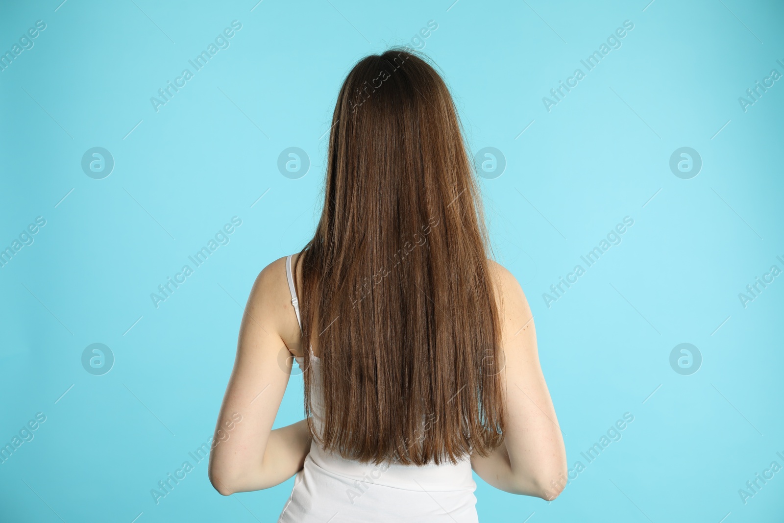 Photo of Woman with long hair on light blue background, back view