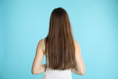 Photo of Woman with long hair on light blue background, back view